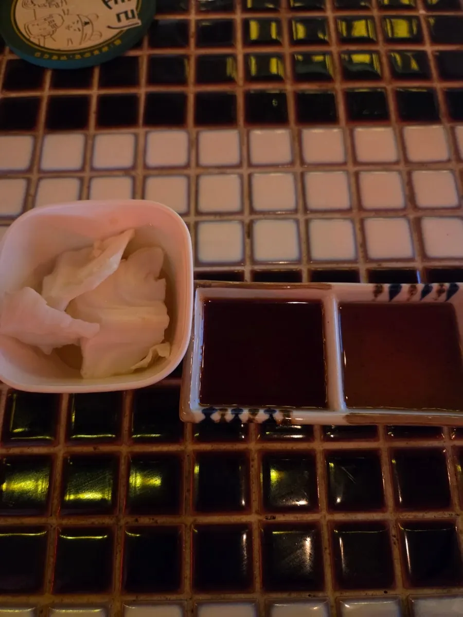 Spicy sauce, soy sauce, and cabbage side dishes on the table