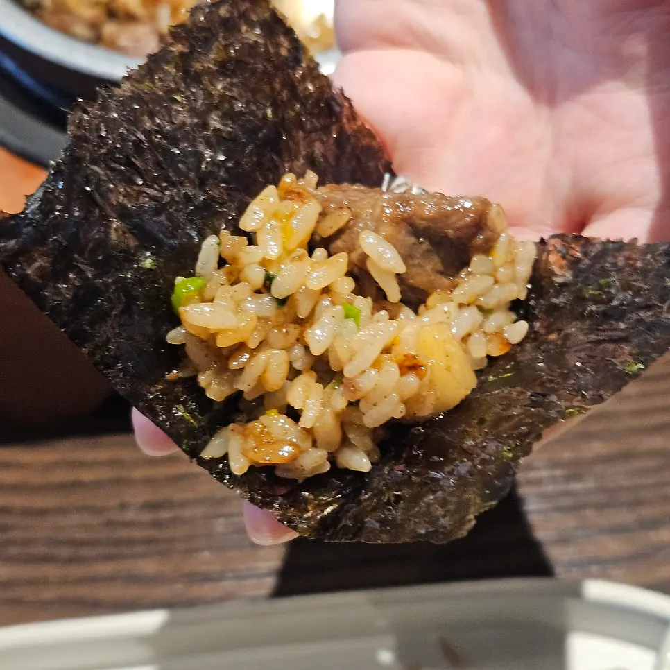 A bite of short rib pot rice wrapped in laver