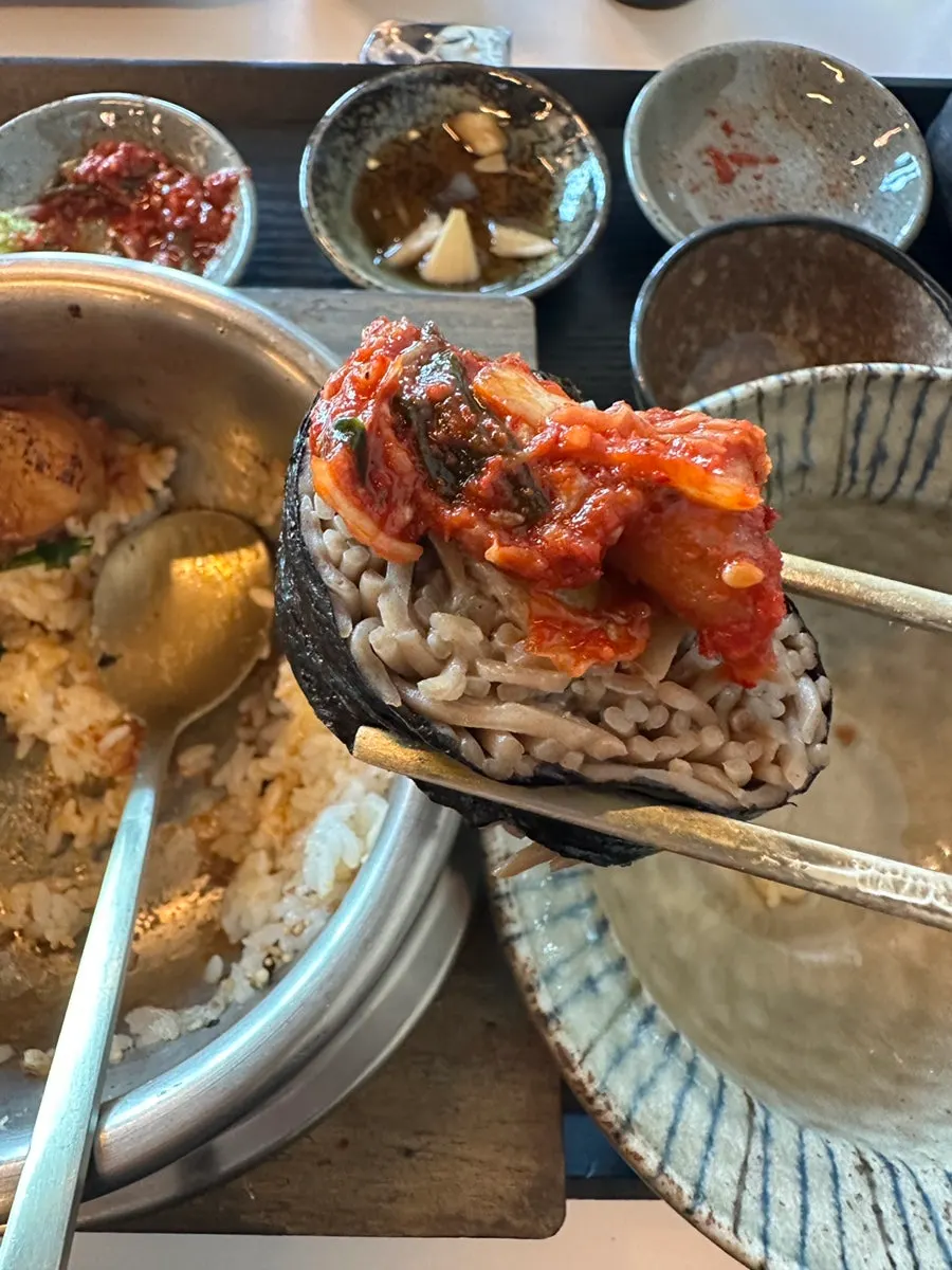 Last bite of buckwheat gimbap topped with kimchi