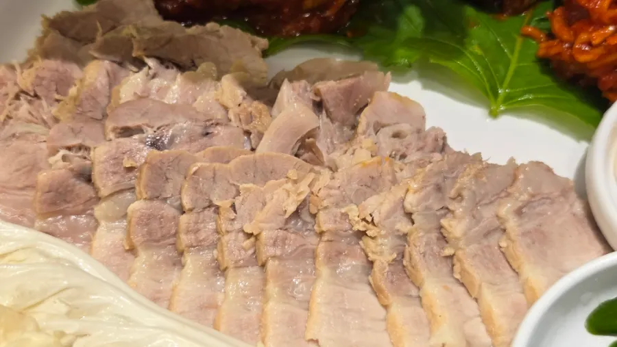 Wrapping bossam with fresh julienned vegetables