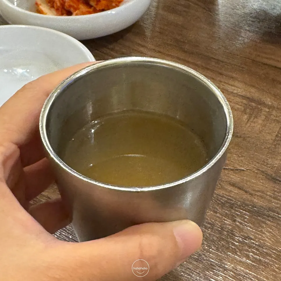 Self-serve bar in the center of the restaurant with banchan and warm broth