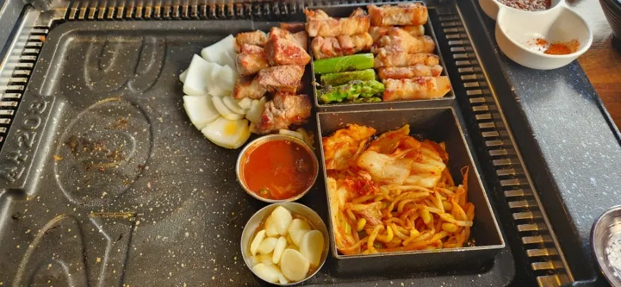 철판 위에 2층으로 쌓아 올린 삼겹살과 아스파라거스
