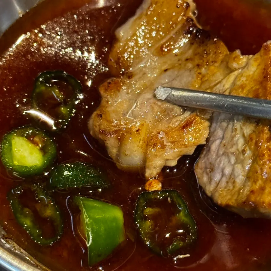 A piece of pork belly dipped in soy meat sauce