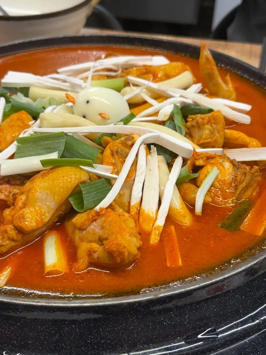 A large pot of dakdoritang with rice cake, potato and scallion
