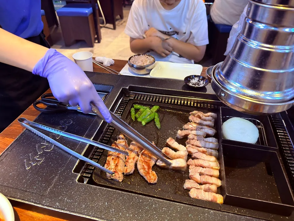 직원이 불판에서 오겹살을 굽는 모습