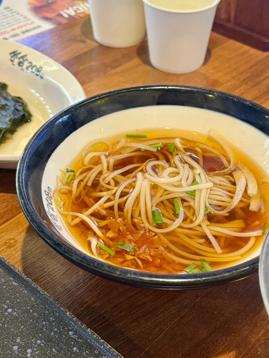 A bowl of rice noodle soup served complimentary at this BBQ restaurant