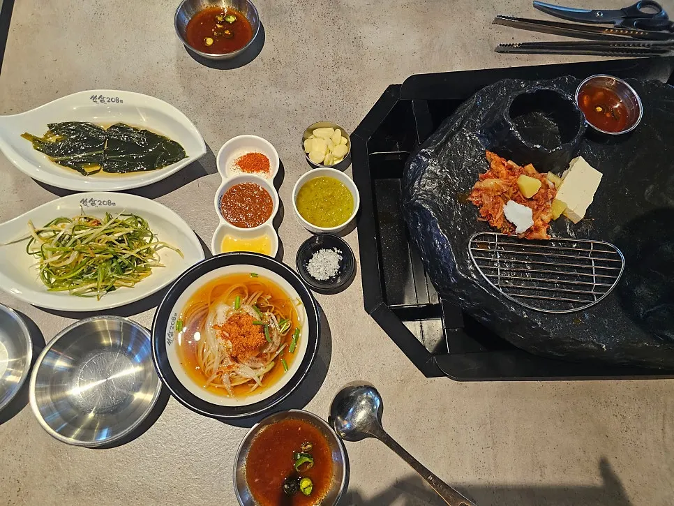 Volcano-shaped stone grill with basic side dishes and various sauces set up
