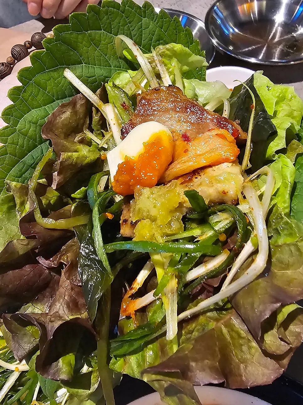 Lettuce wrap with meat, scallion strips, and garlic