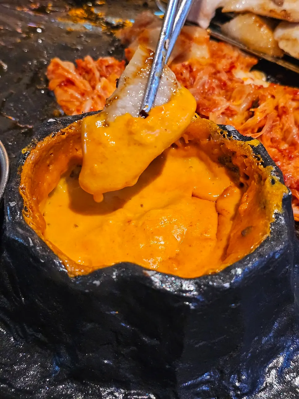 A piece of pork belly with cheese stretching off it