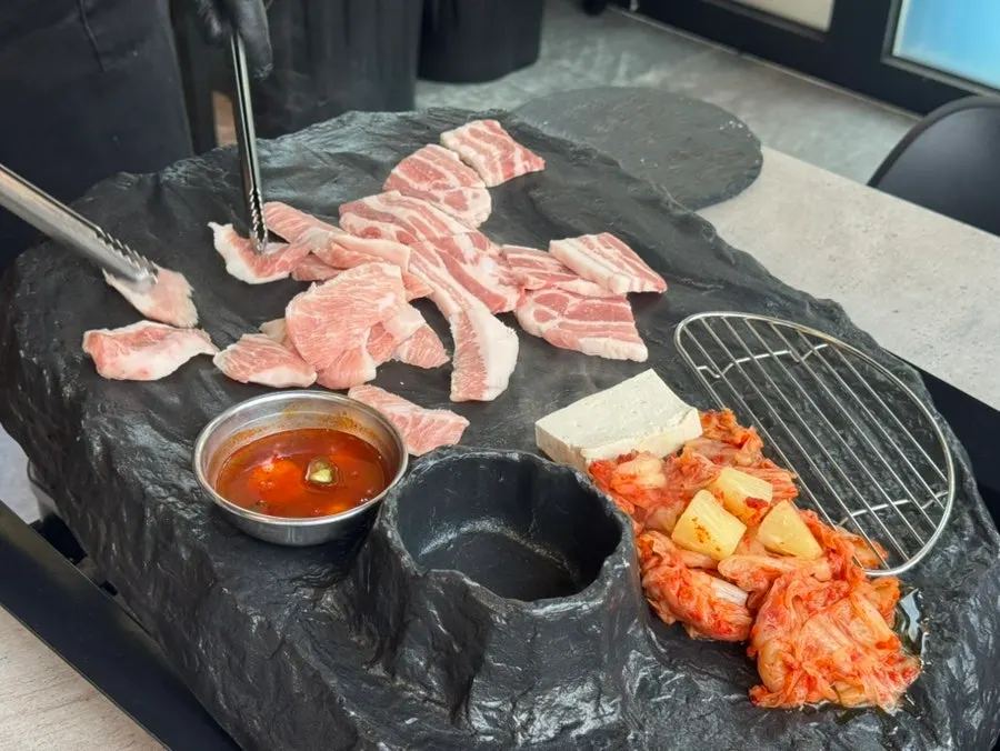 Staff member grilling pork belly on the stone plate