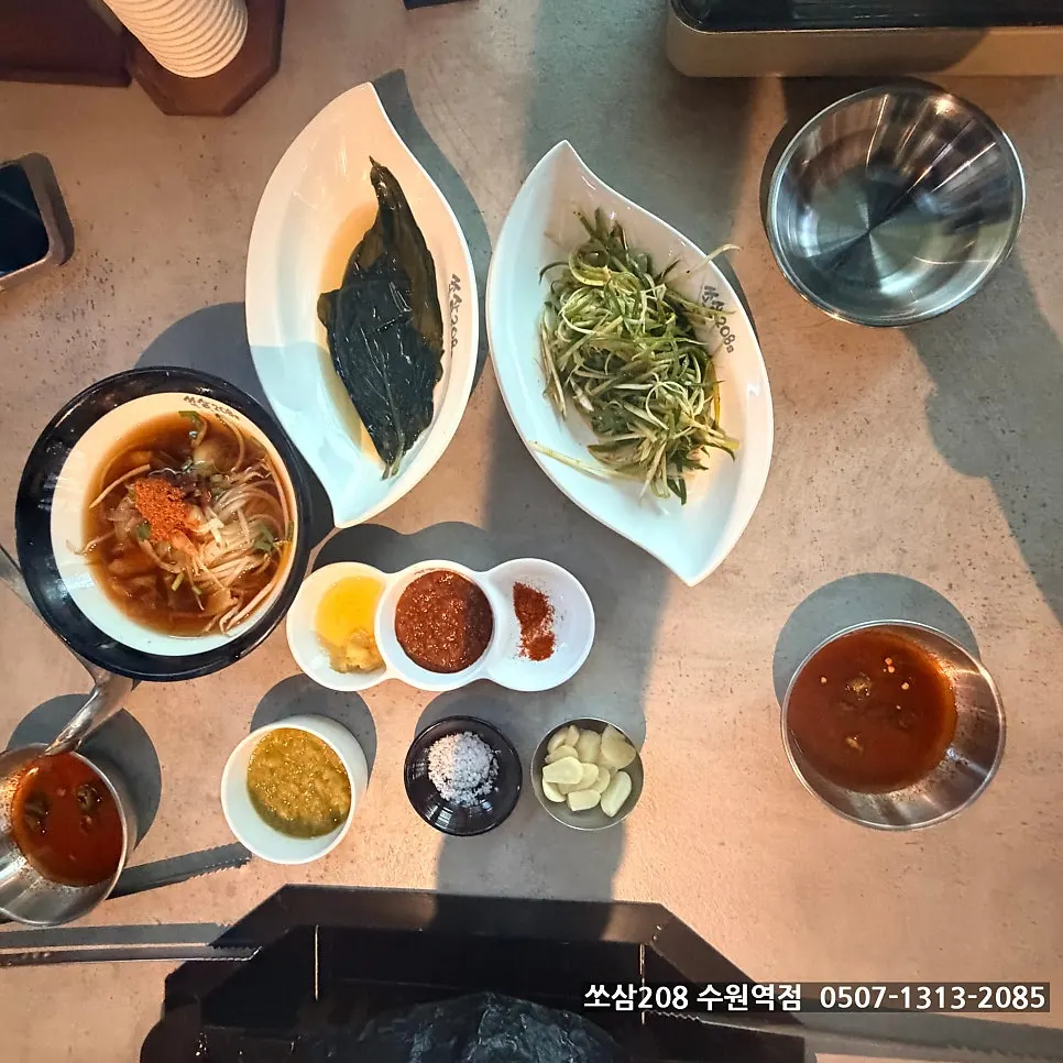 Full spread of Ssosam 208's basic side dishes including lettuce, scallion strips and wild garlic leaves