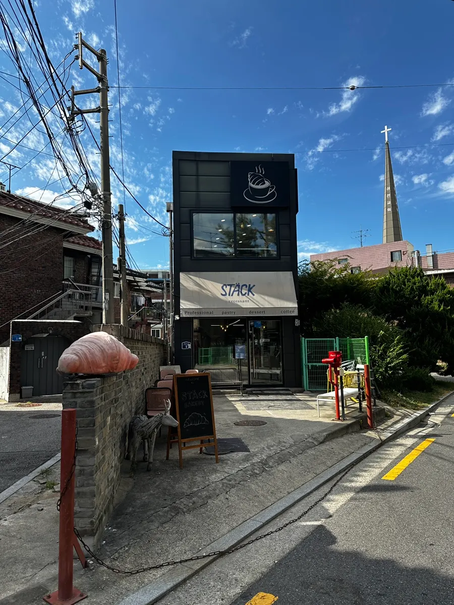 파란 하늘 아래 블랙 톤 2층 건물인 스택베이커리 외관