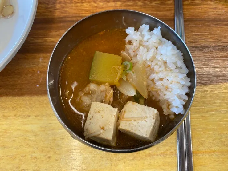 A bite of mul naengmyeon lifted with chopsticks
