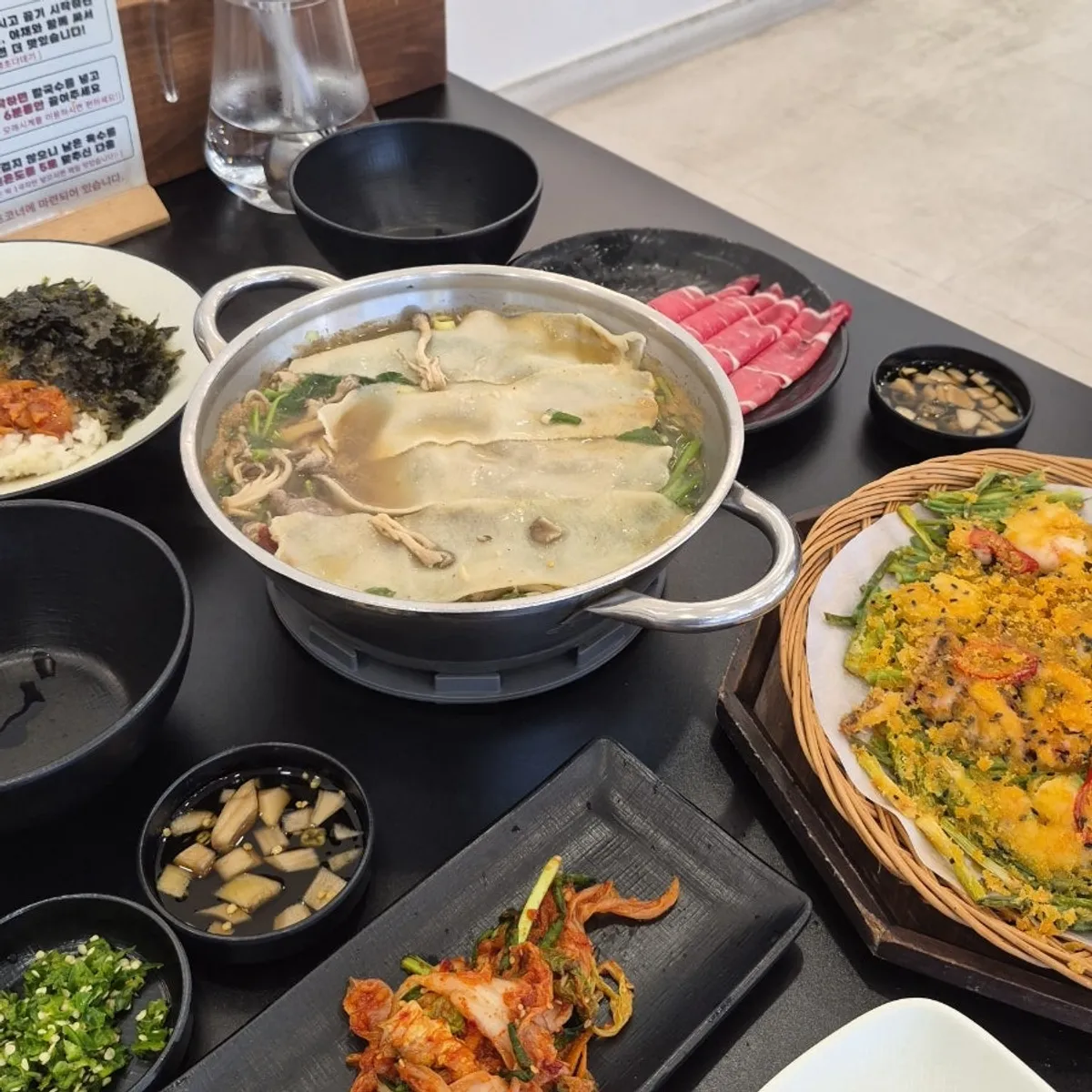 A bite of flat kalguksu wrapped with meat and vegetables