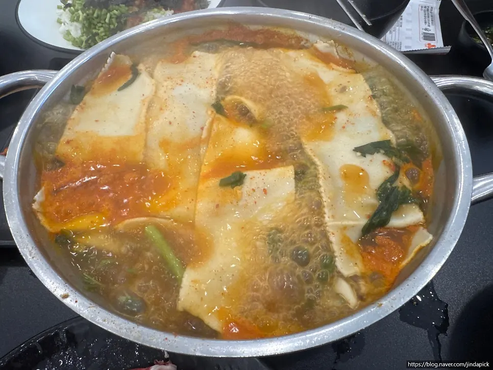 Bowl of kalguksu noodles lifted from the red broth