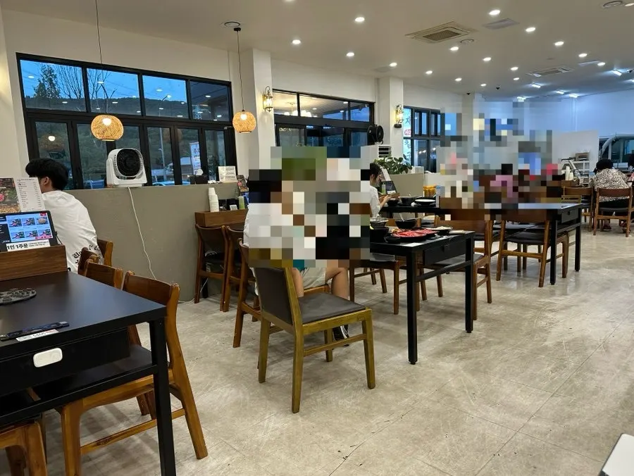 화이트톤 벽면과 우드 테이블의 매장 실내
