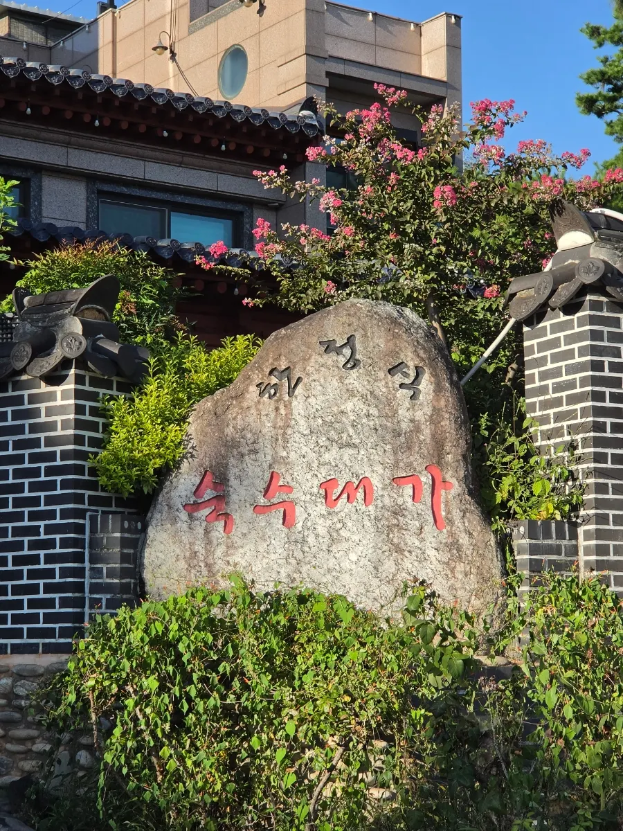 Hanok entrance of Suksudaega with pine trees and garden