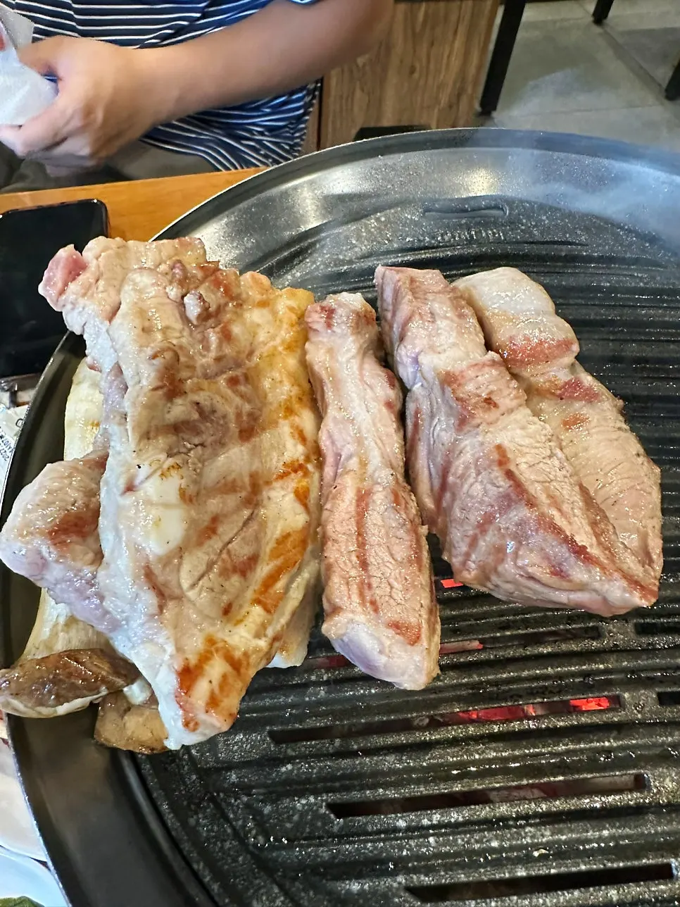 Meat grilling on the barbecue by a staff member