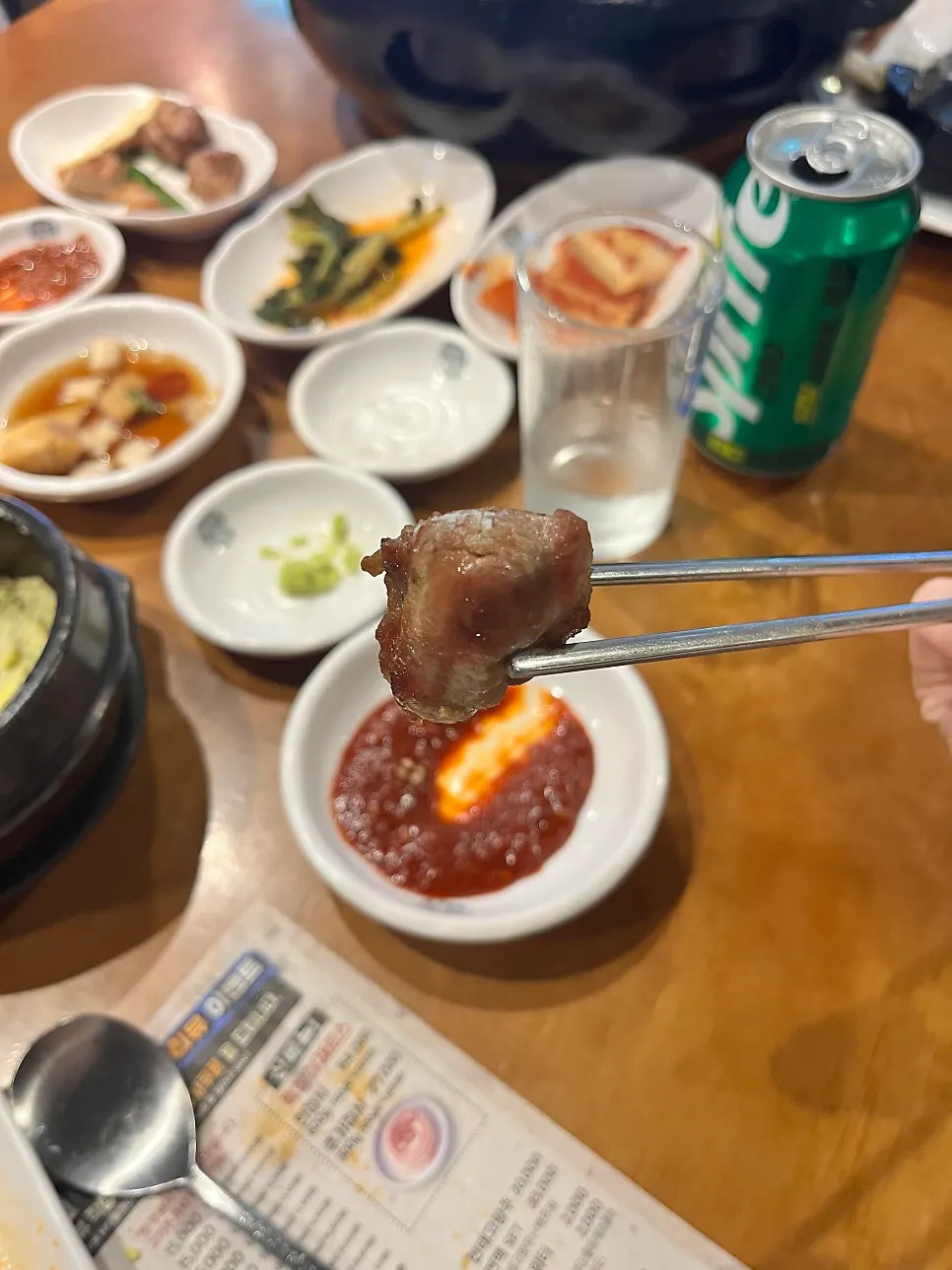 A grilled piece of meat held with tongs