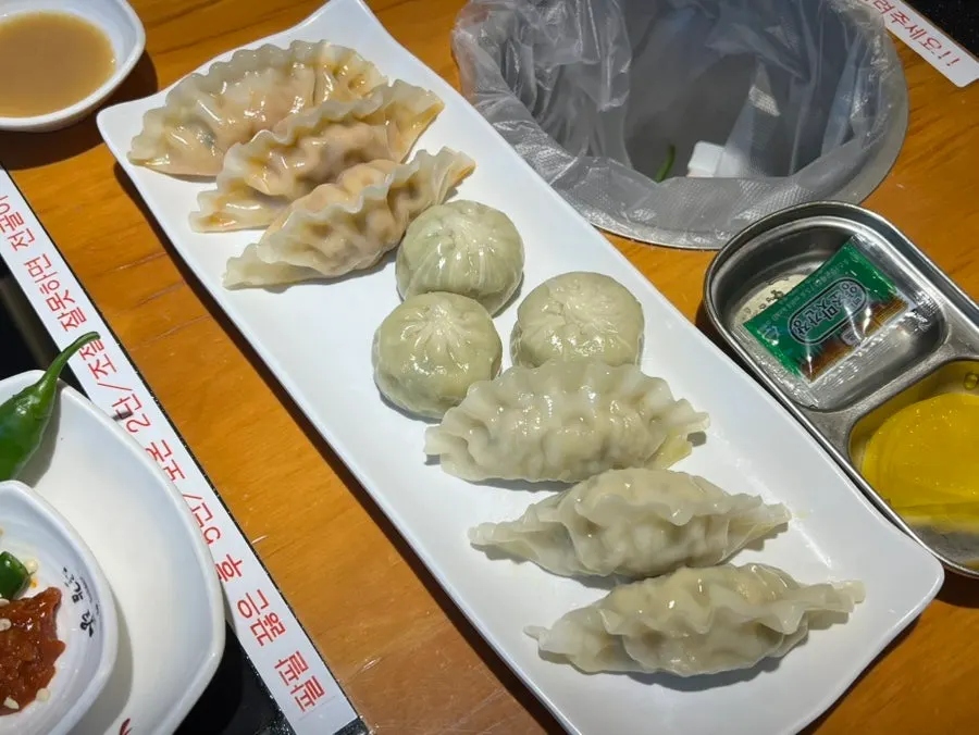 A plate with kimchi, meat, and shrimp dumplings, three kinds