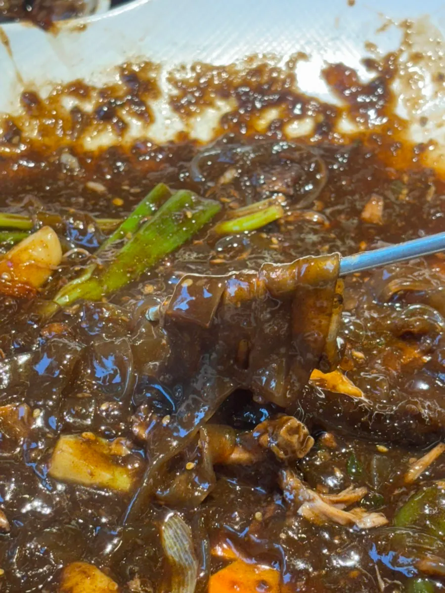 A bite combining meat and glass noodles from the bone stew