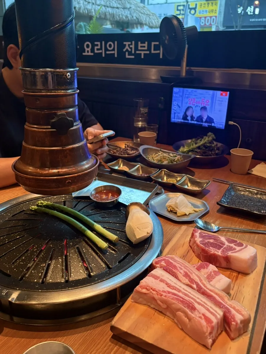Staff member grilling black pork over charcoal