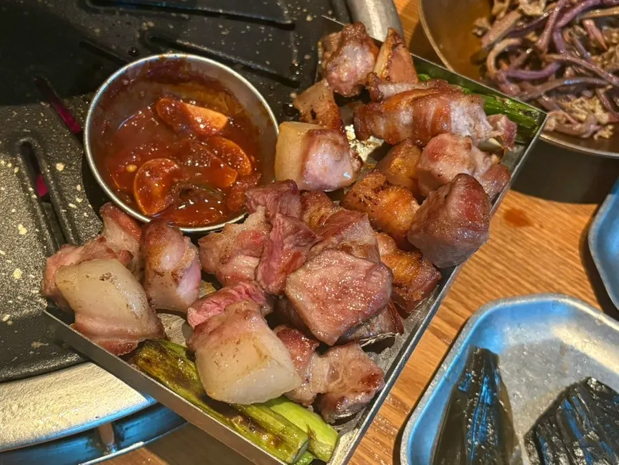 A bite of black pork with wraps and sauces