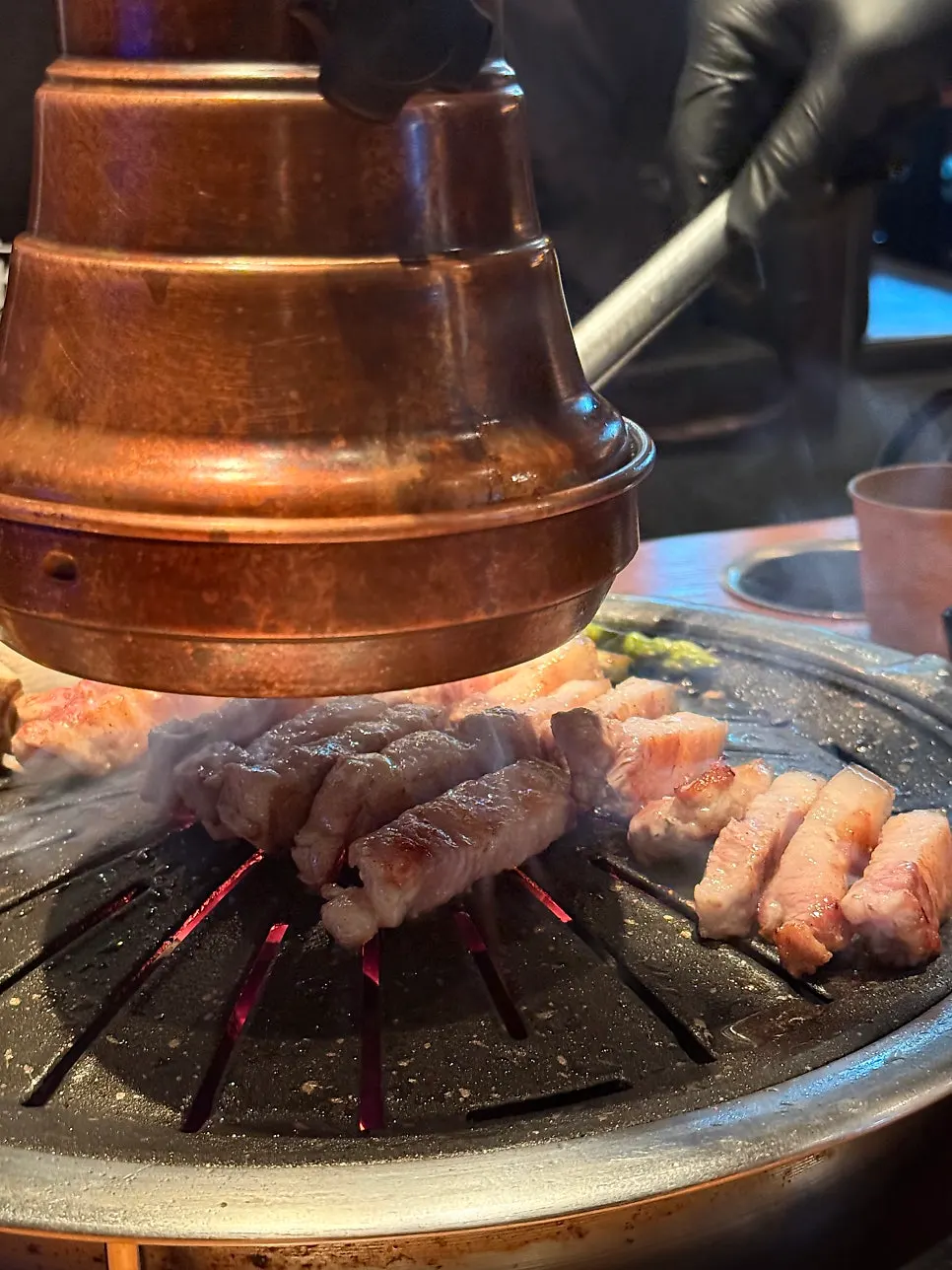 Black pork samgyeopsal cooking on the grill