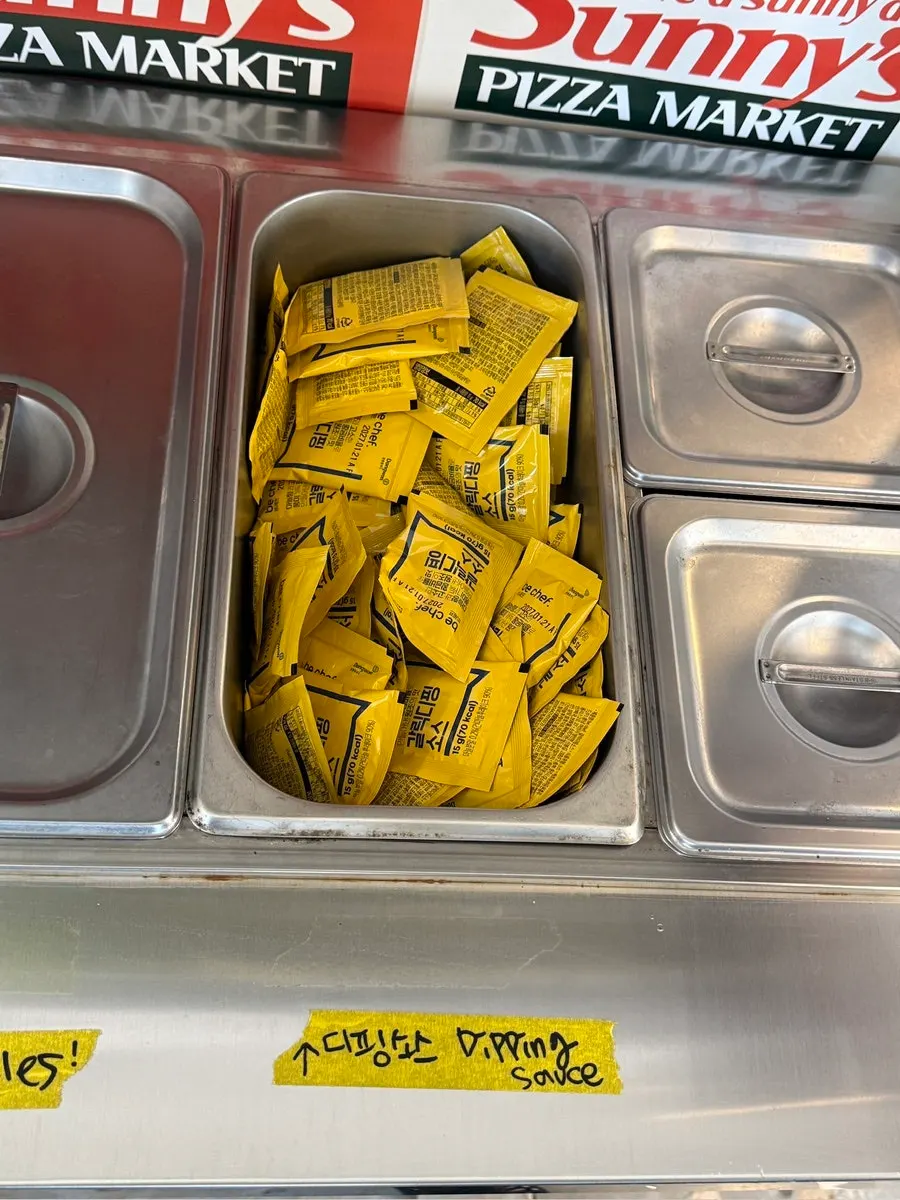 Self-serve sauce bar with hot sauce and parmesan cheese