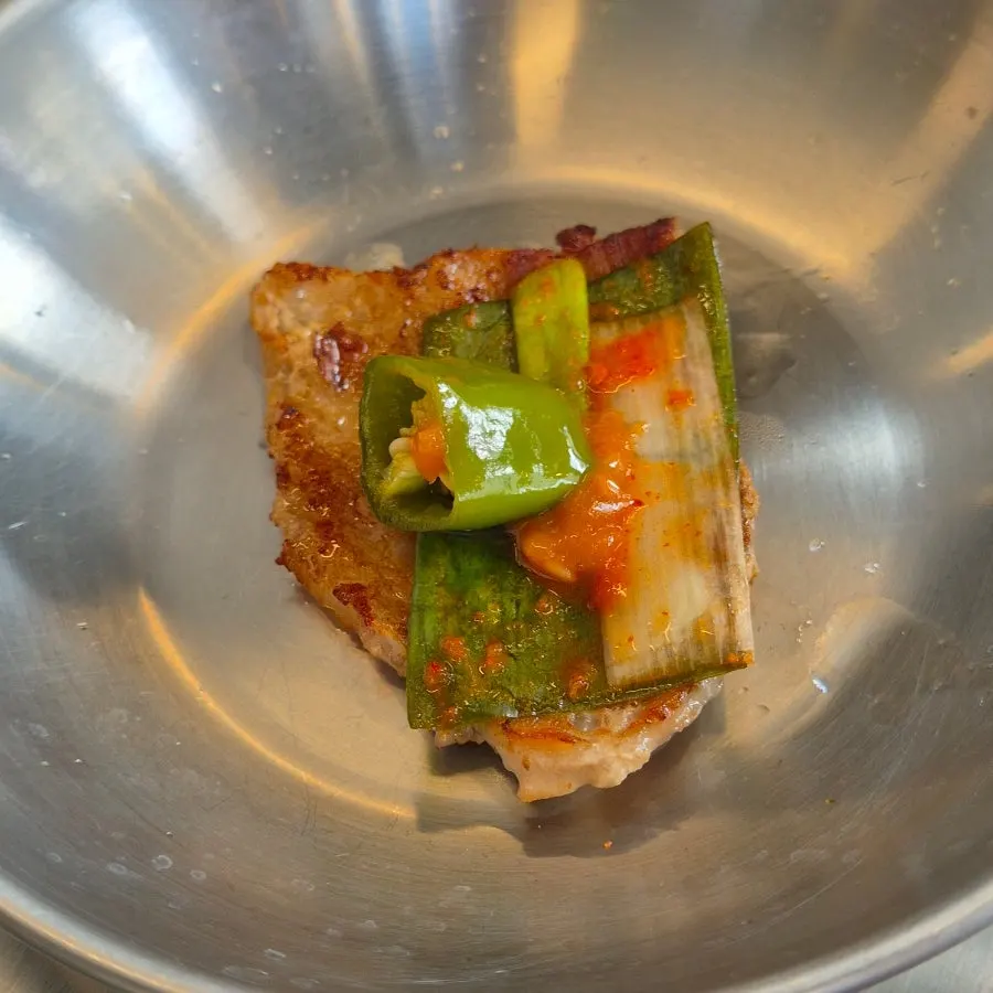 A piece of pork belly dipped in sesame oil sauce