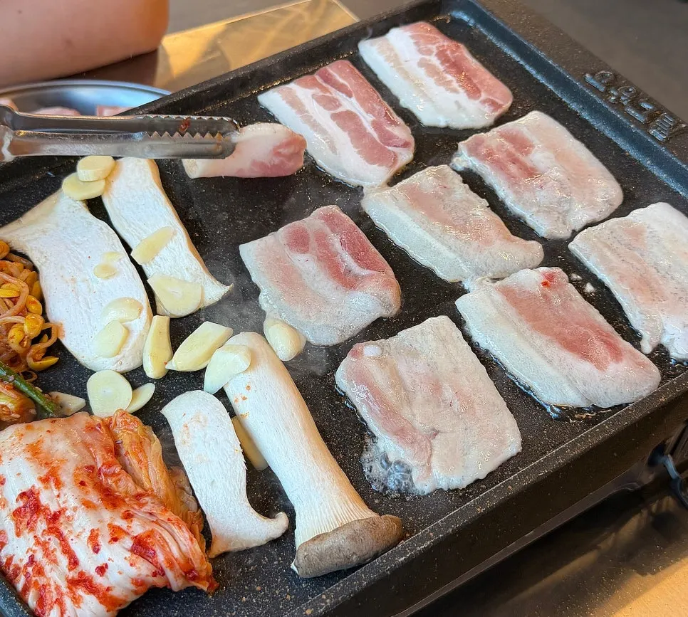 불판에 올린 냉삼과 김치, 콩나물, 버섯