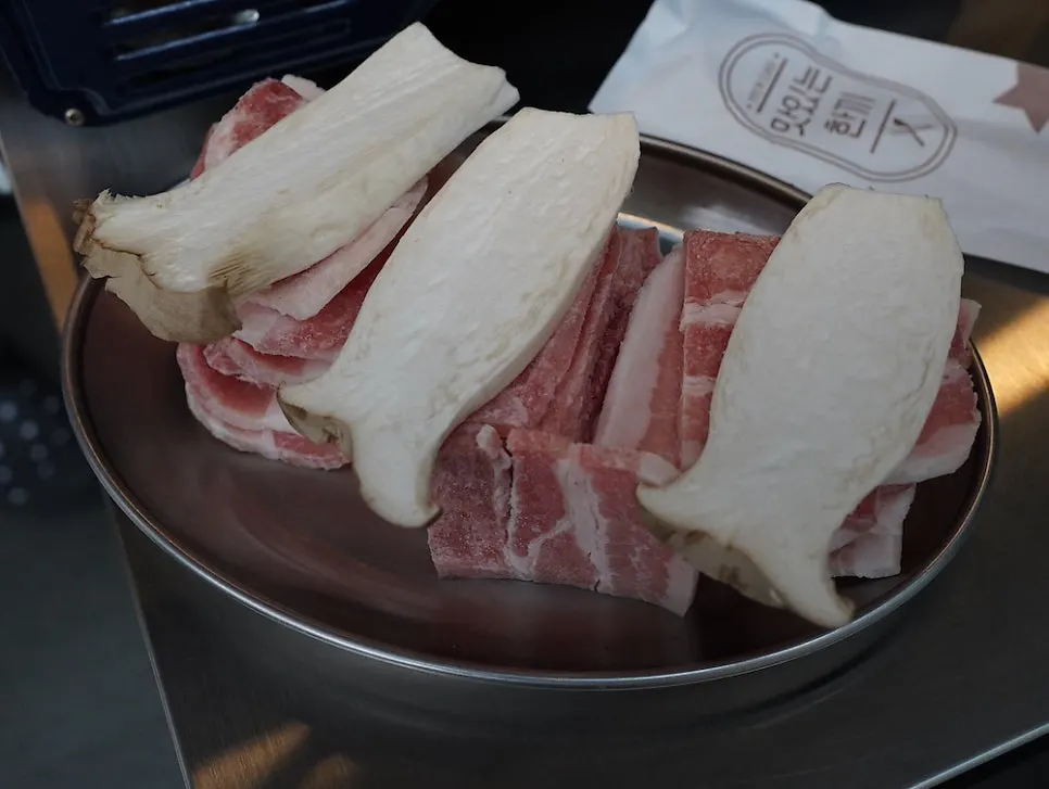 Three servings of frozen pork belly with a plate of mushrooms