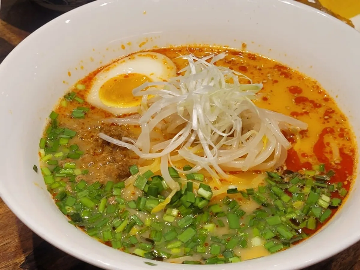 A bowl of tantanmen topped with egg noodles and ground meat