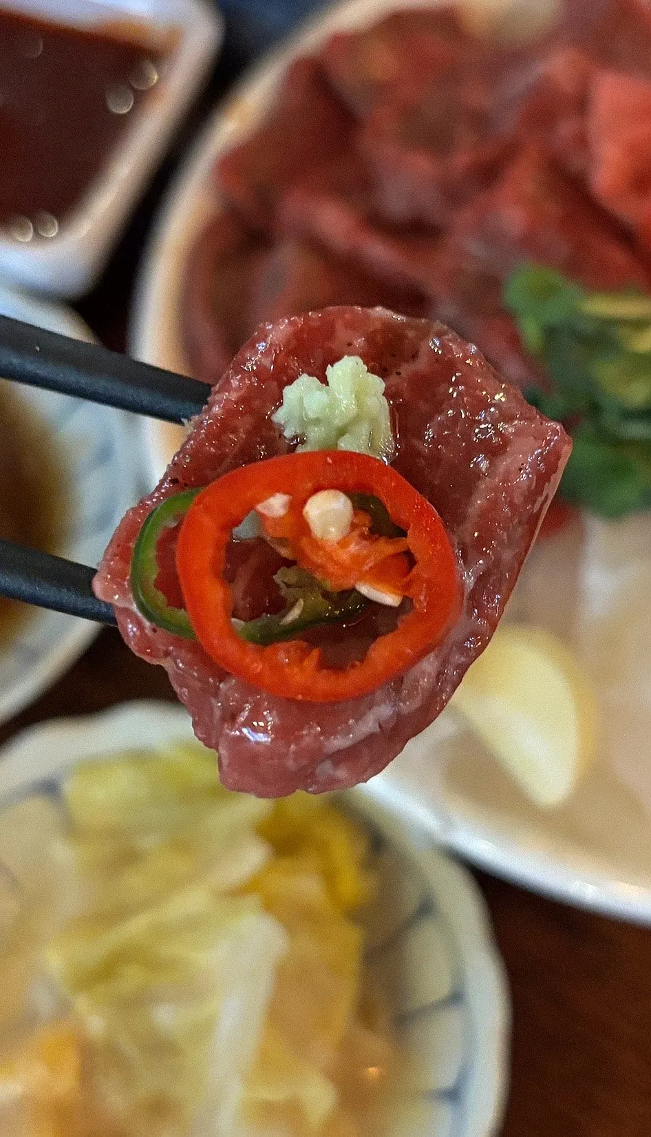 A piece of yuksashimi dipped in sesame oil sauce