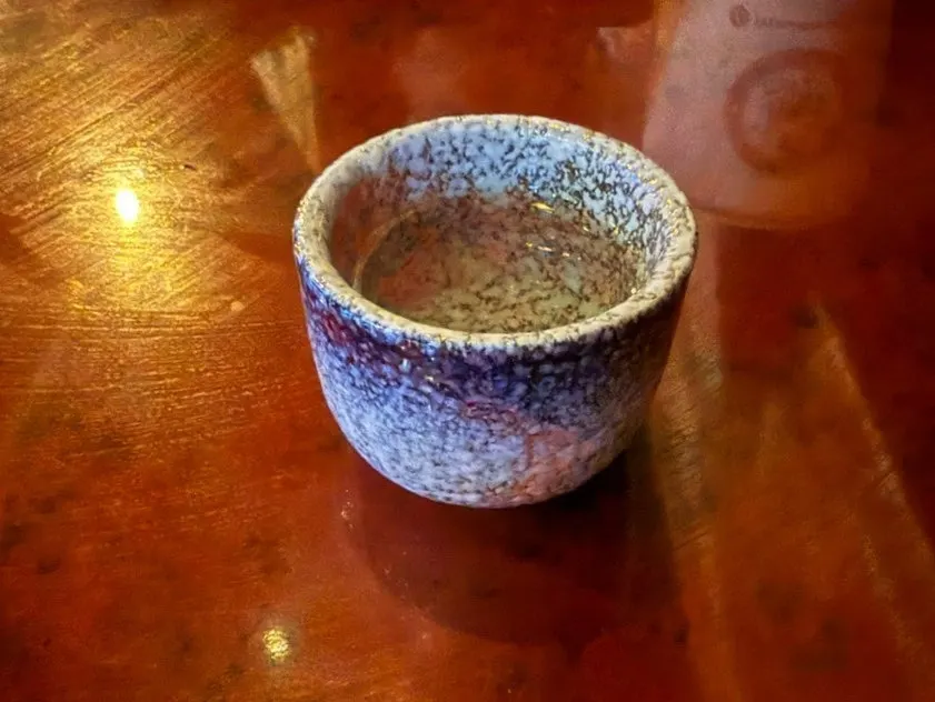 A welcome glass of sake next to the whale sake bottle