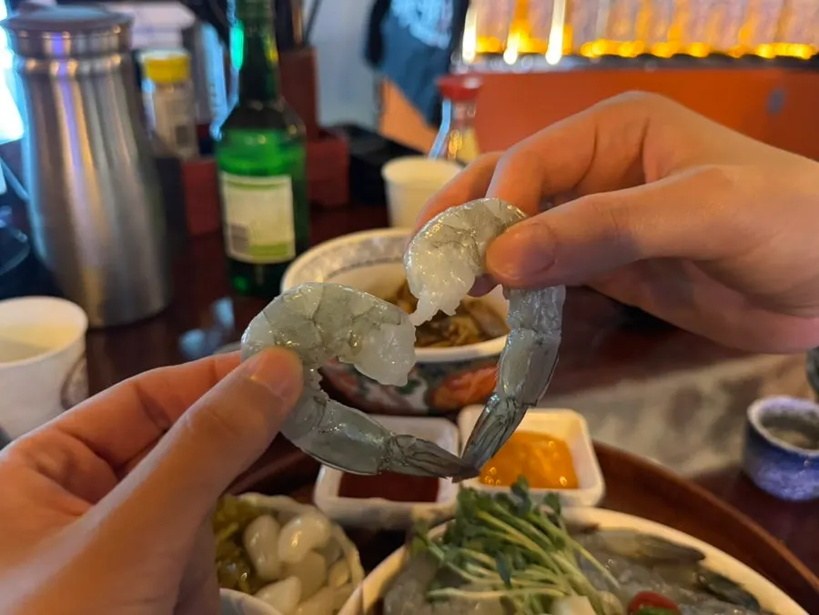 Raw shrimp sashimi picked up with chopsticks