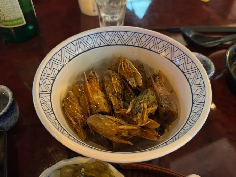 Peeling the shell off a fried shrimp head held in hand