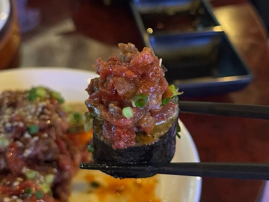 A single bite of maki topped with yukhoe