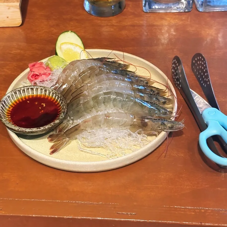 A plate of fully peeled live raw shrimp sashimi