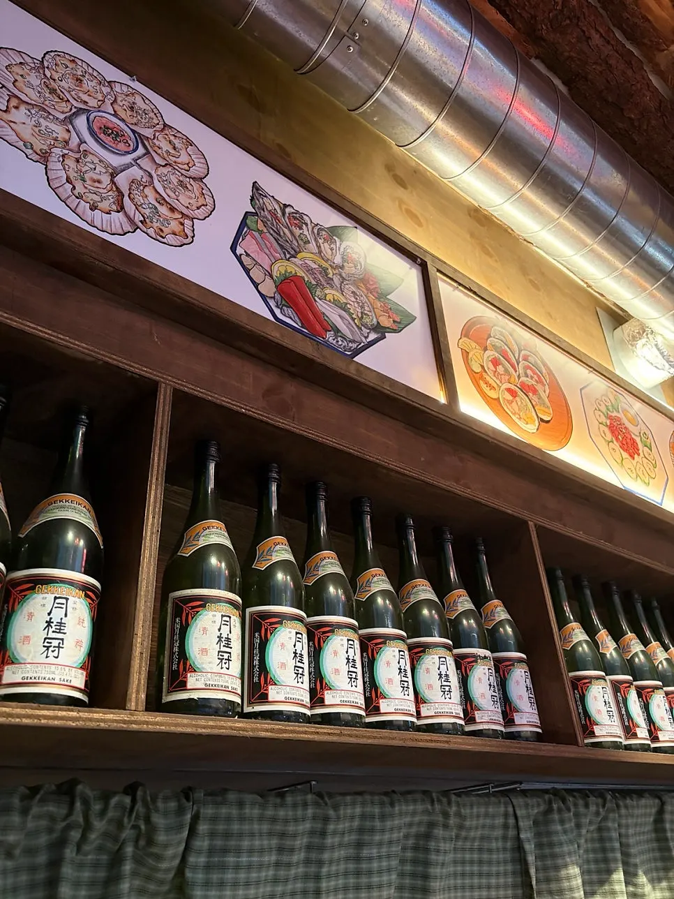 목재 인테리어와 사케병이 놓인 수산장 고잔점 내부