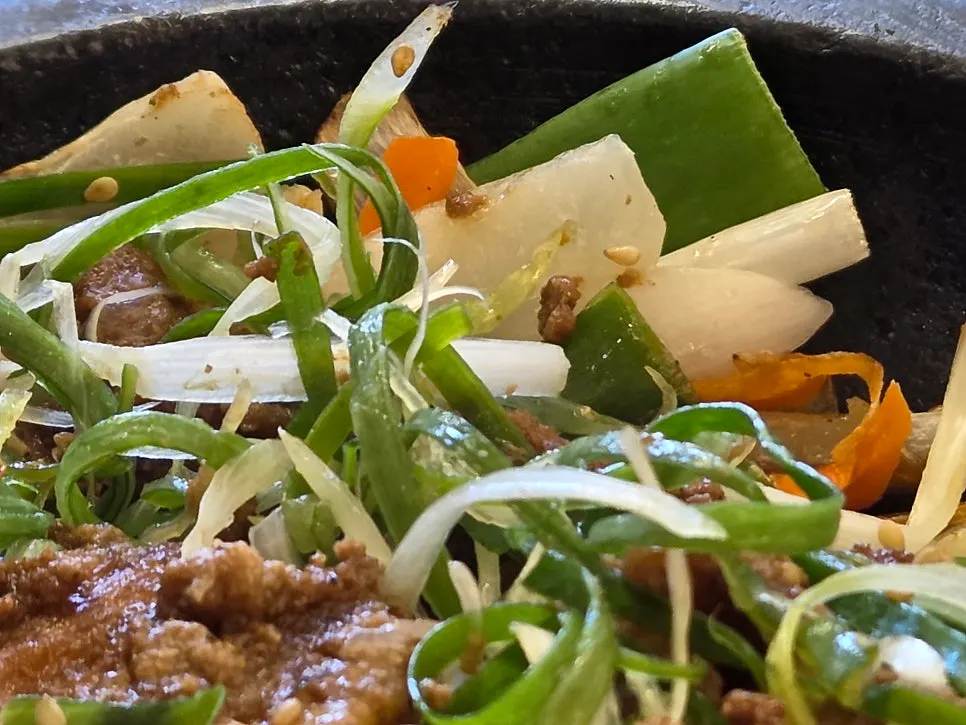 Seokgalbi on a stone plate with onions and shredded scallions