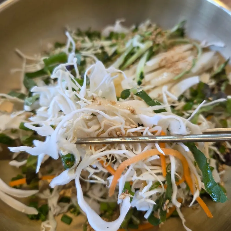 A bowl of perilla leaves, lettuce, cabbage, and seaweed flakes