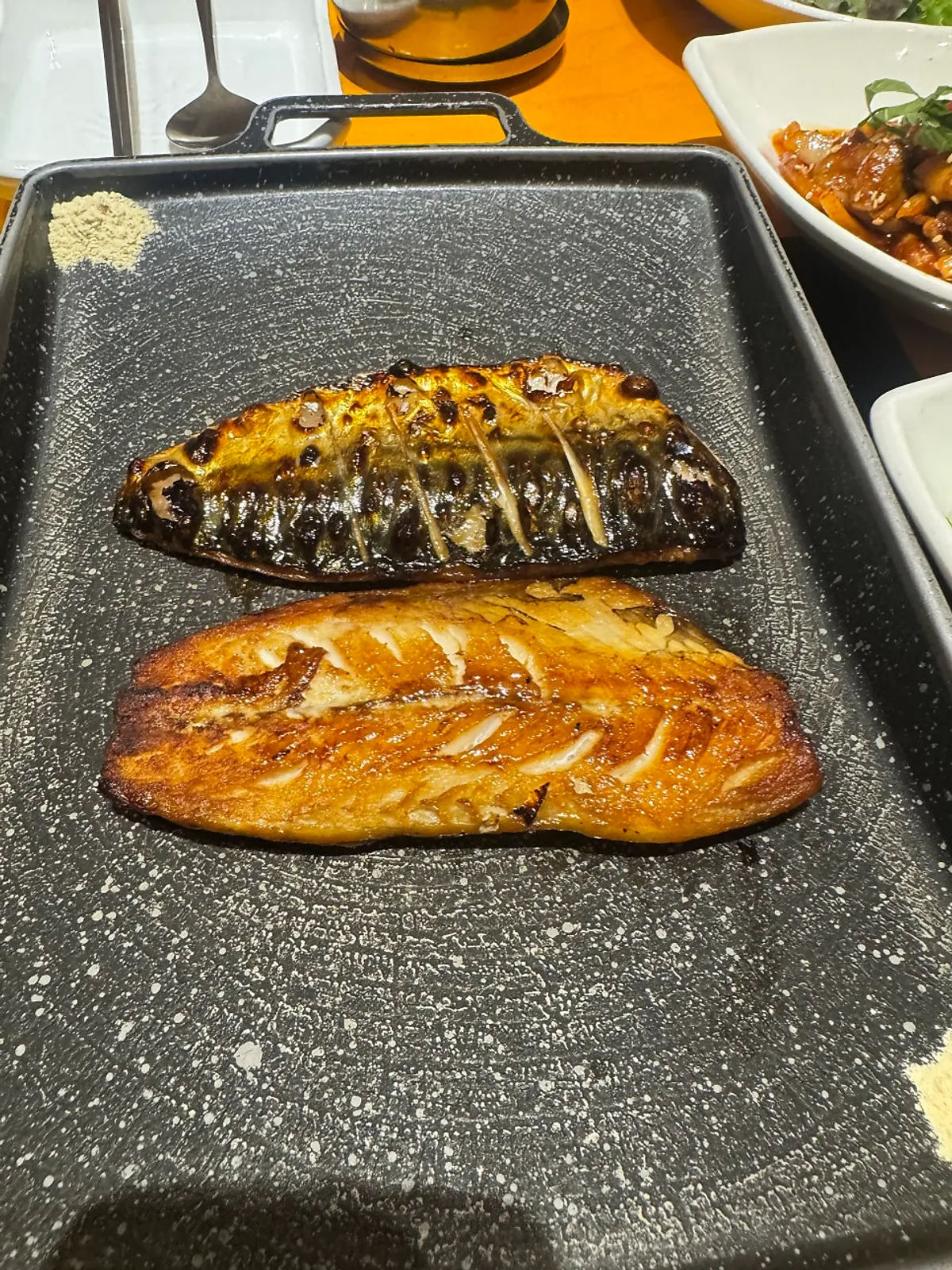 Wood-fired mackerel on the grill plate over an induction burner