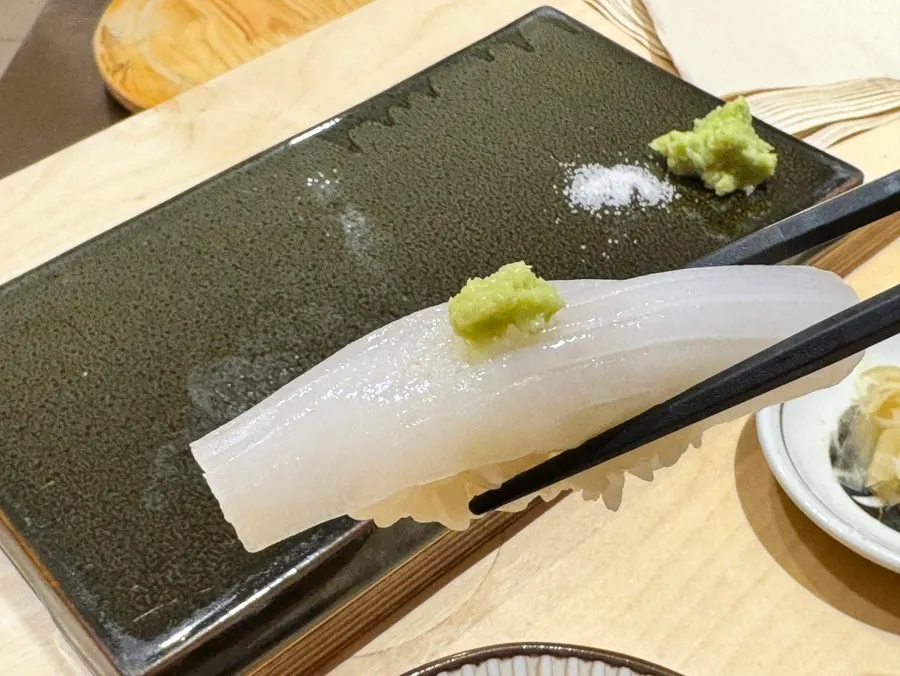 Squid nigiri topped with roasted sesame