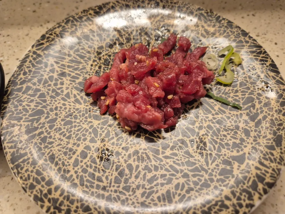 A plate of salmon beef tartare roll sushi