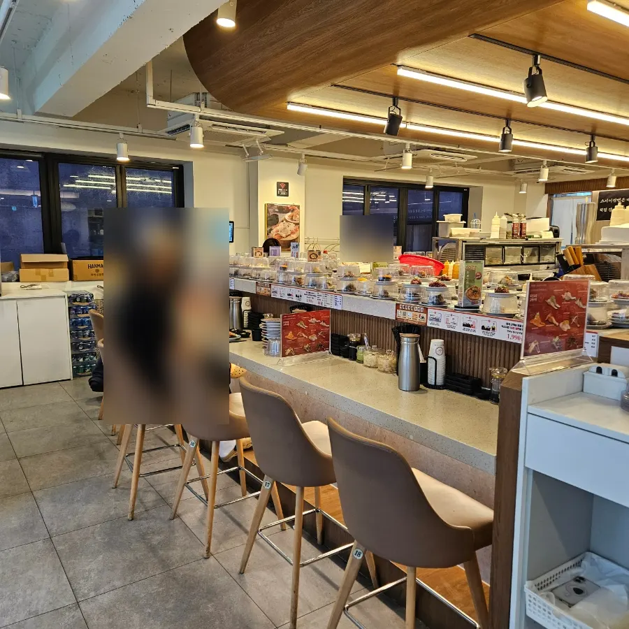 Customers seated at the conveyor-belt sushi bar seats