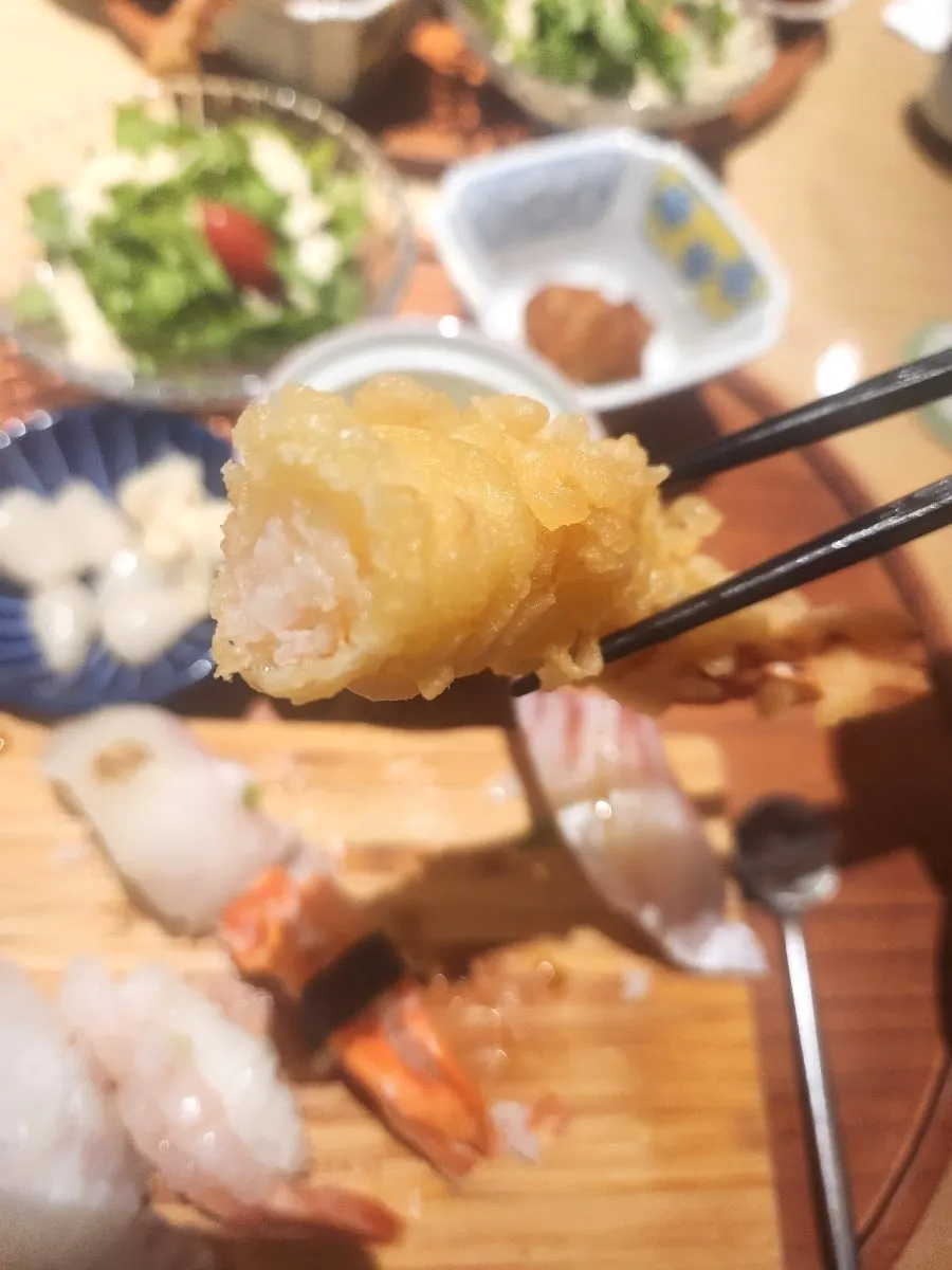 A single piece of sushi picked up with chopsticks