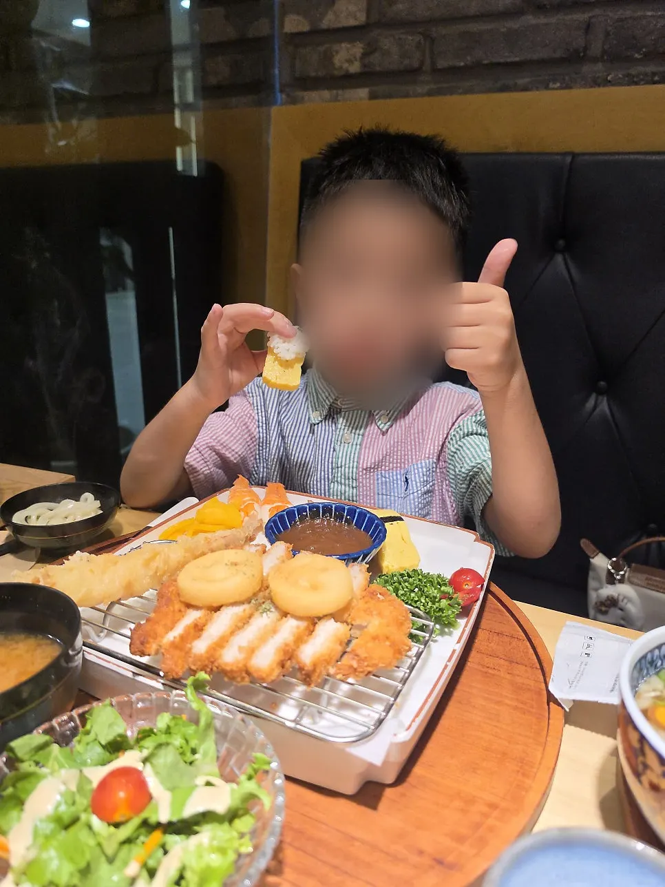 A child giving a thumbs up while eating sushi