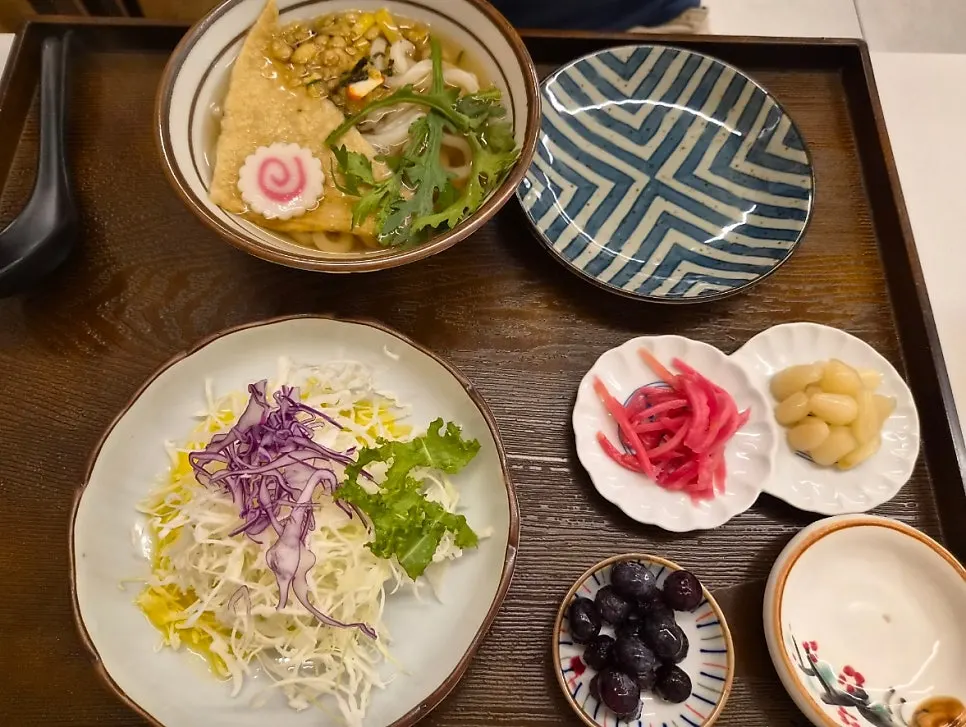 Flame sushi set table spread with salad, udon, and cold soba