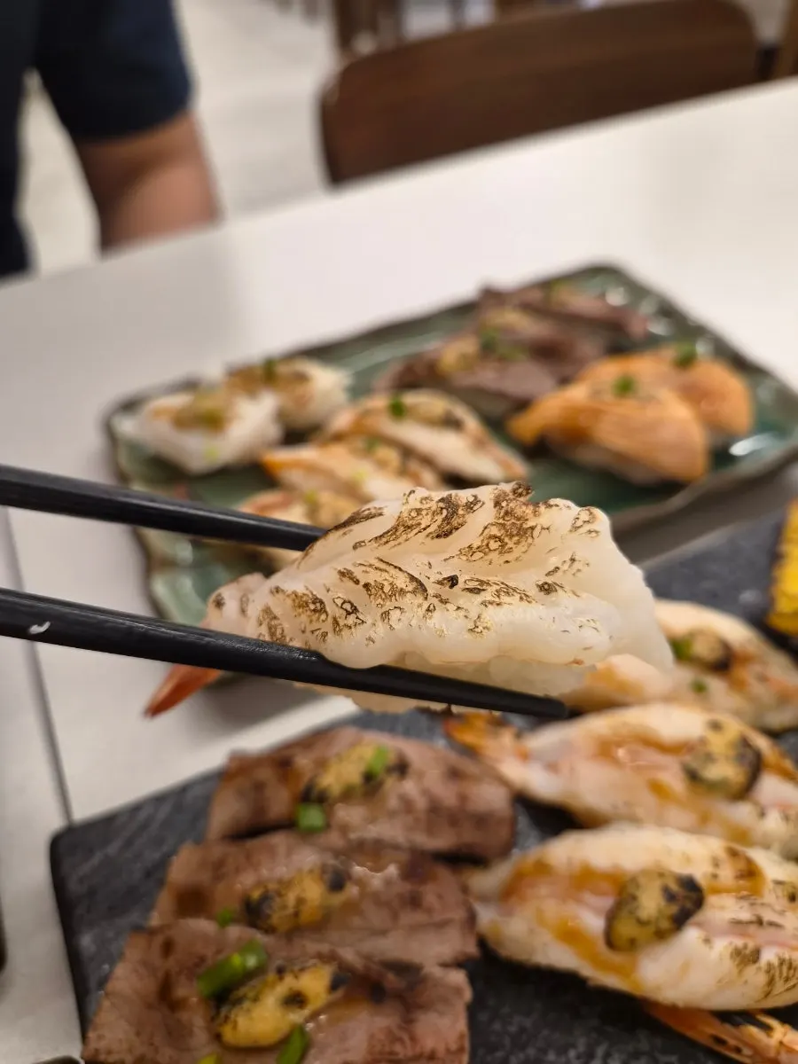 A piece of flame sushi topped with garlic sauce